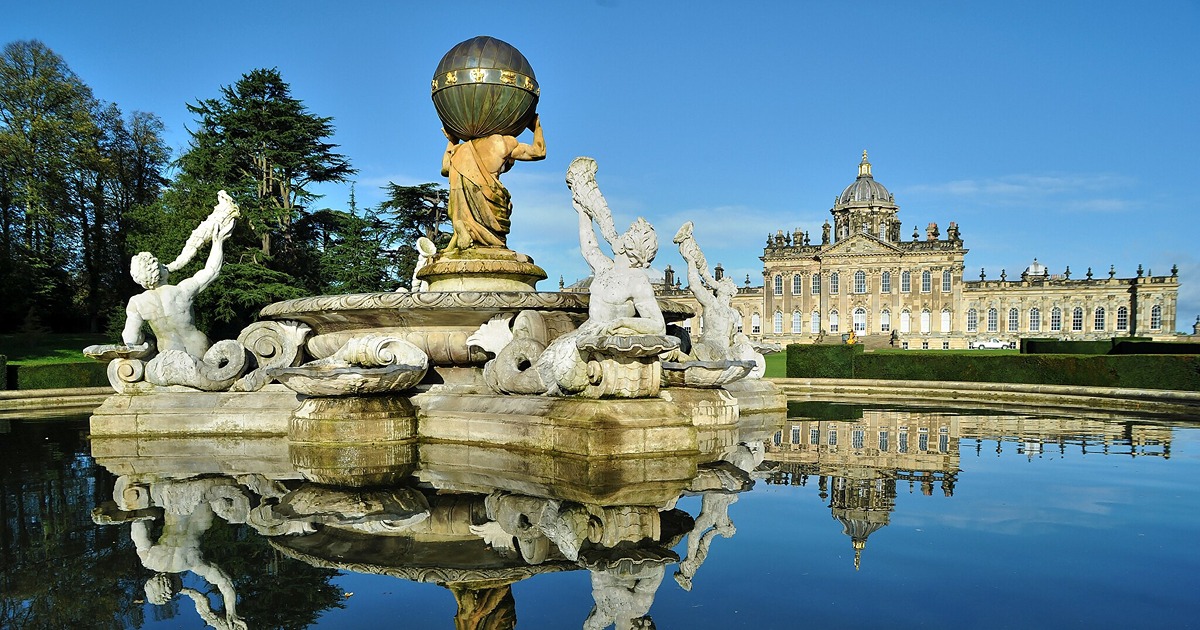 An ornate classical fountain in the foreground, and far beyond, a baroque country house